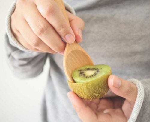 Person scooping out a kiwifruit