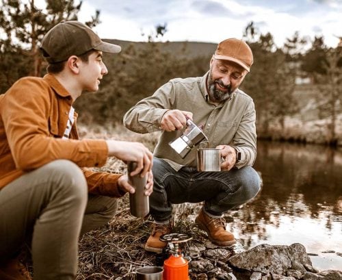 Father pour son coffee in the wilderness by a river