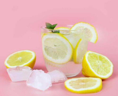 Glass of lemon water with sliced lemons and ice cubes