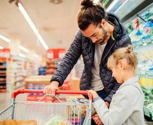 Father and daughter supermarket shopping, reading labels